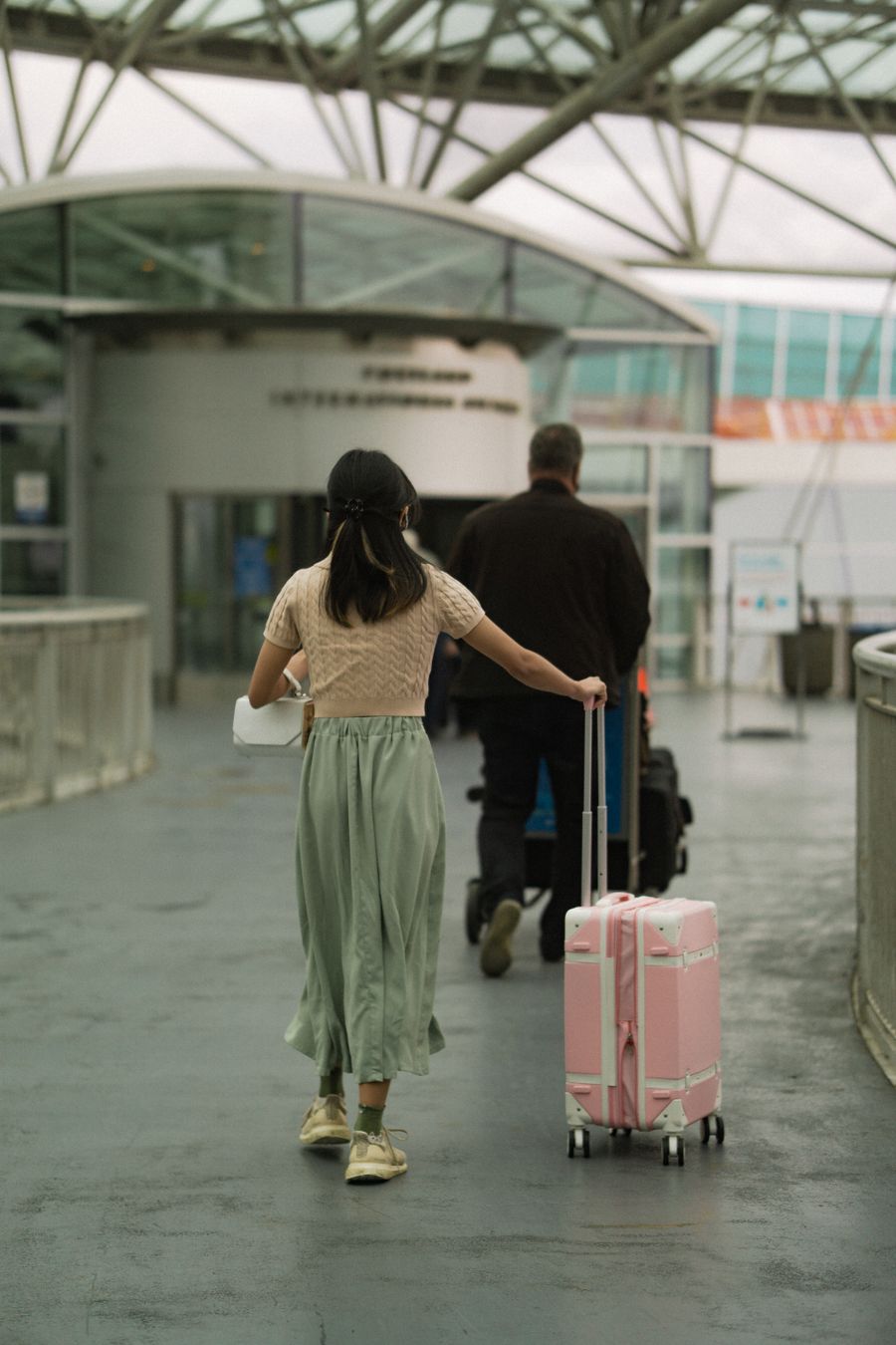 woman in brown t shirt pushing her pink luggage and man in black long sleeves pushing trolley — Developers: Perdido na medina, achado pelo GPS: o ponto azul nunca mente.