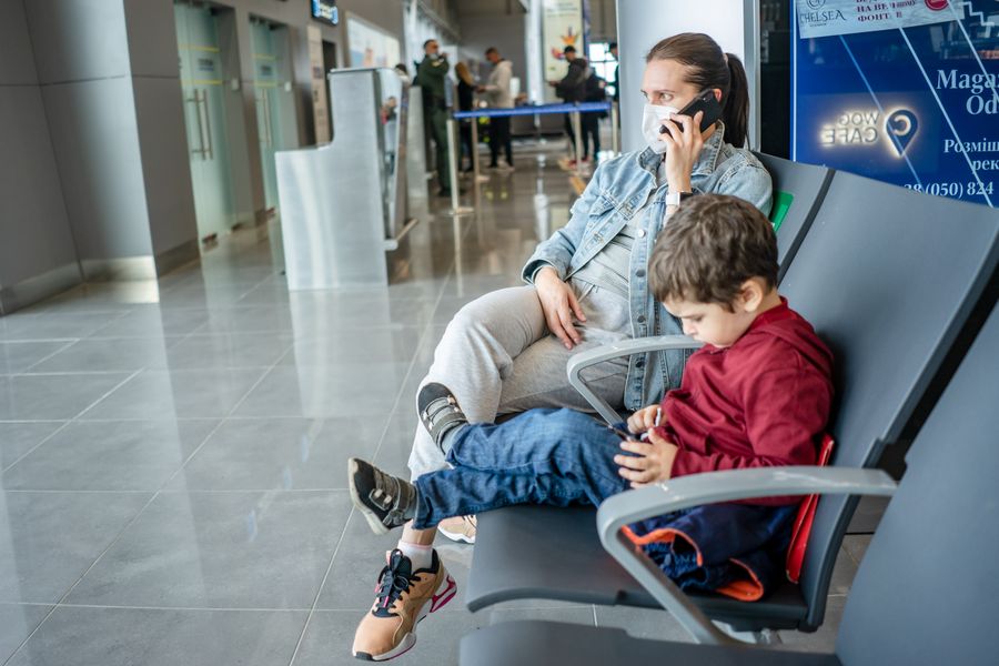 mother and son waiting at the airport — Sem plástico para perder, sem bandeja para abrir.