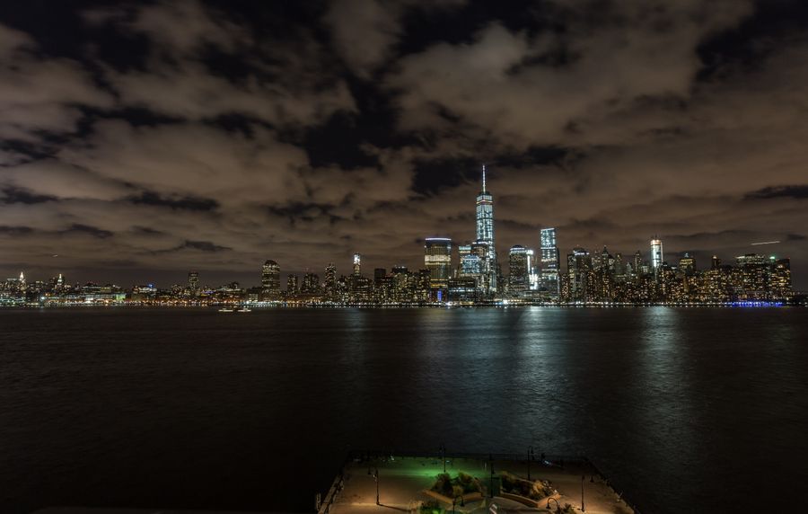 new york cityscape behind sea at night — Docs: Feiras noturnas e trens tardios — conectado o caminho todo.