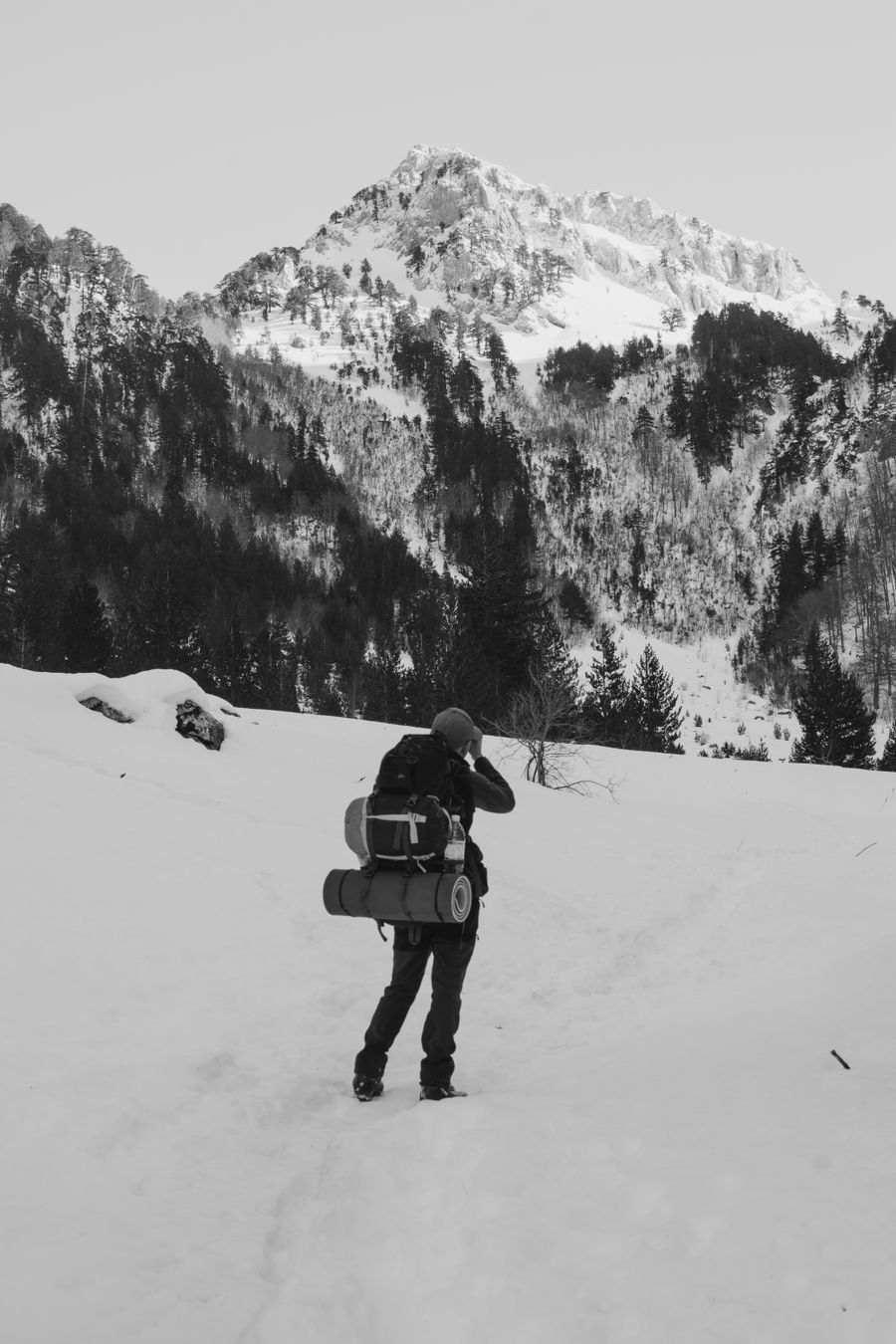 back view of a person with a backpack hiking in snowy mountains — Viagens de negócios: dimensionamento de hotspot, orçamentos de videochamada, saltos entre países.