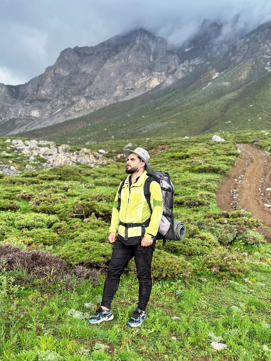 man wearing yellow jacket in a mountain valley — O skyline de COUNTRY ao entardecer: videochamada para casa com a cidade inteira atrás.