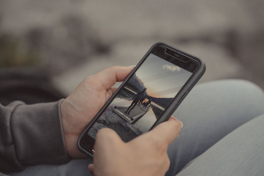Close-up of hands holding a smartphone showing a mountain scene, captured outdoors in Banff. — Noites em Cabo Verde: planos de jantar, corridas e avaliações, tudo na hora.