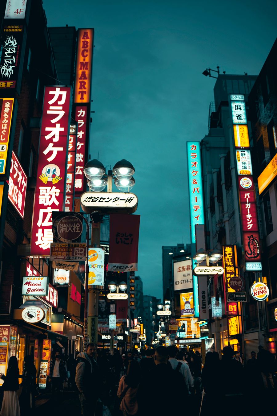 pedestrians walk street in asian city at night — Coworking abroad: laptop tethered, calls crisp, deadlines met.