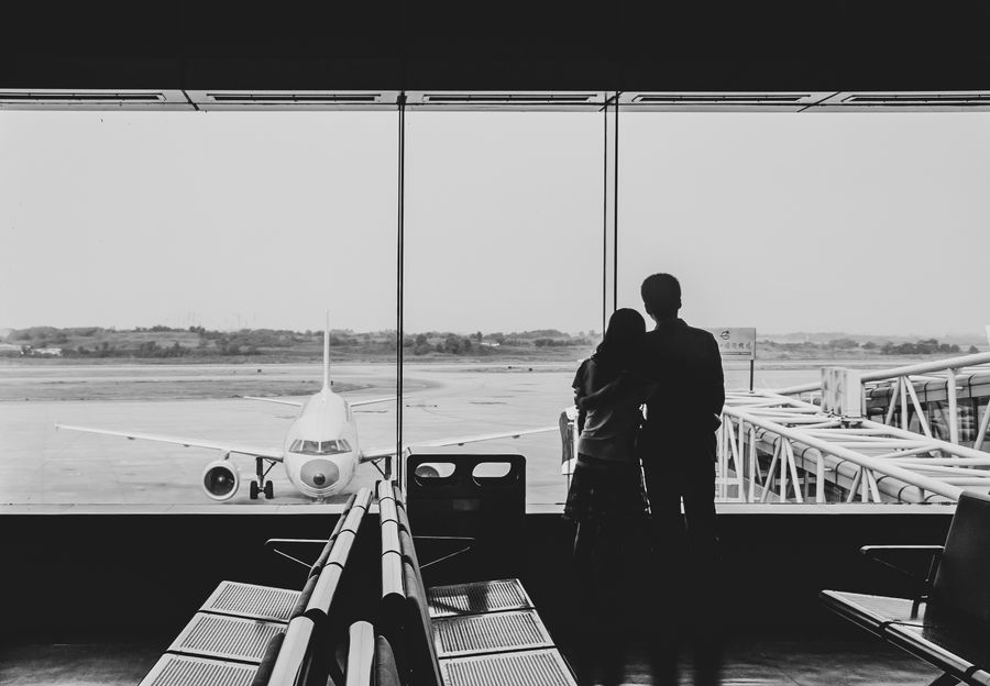 back view of couple embracing at airport — Seu número de viagem funciona no momento em que o eSIM ativa.
