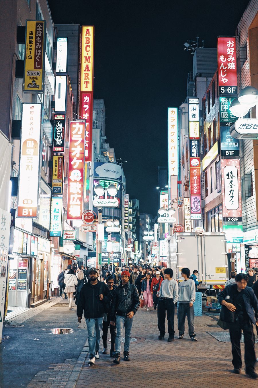 view of a crowded shibuya district at night tokyo japan — O skyline de Timor-Leste ao entardecer: videochamada para casa com a cidade inteira atrás.