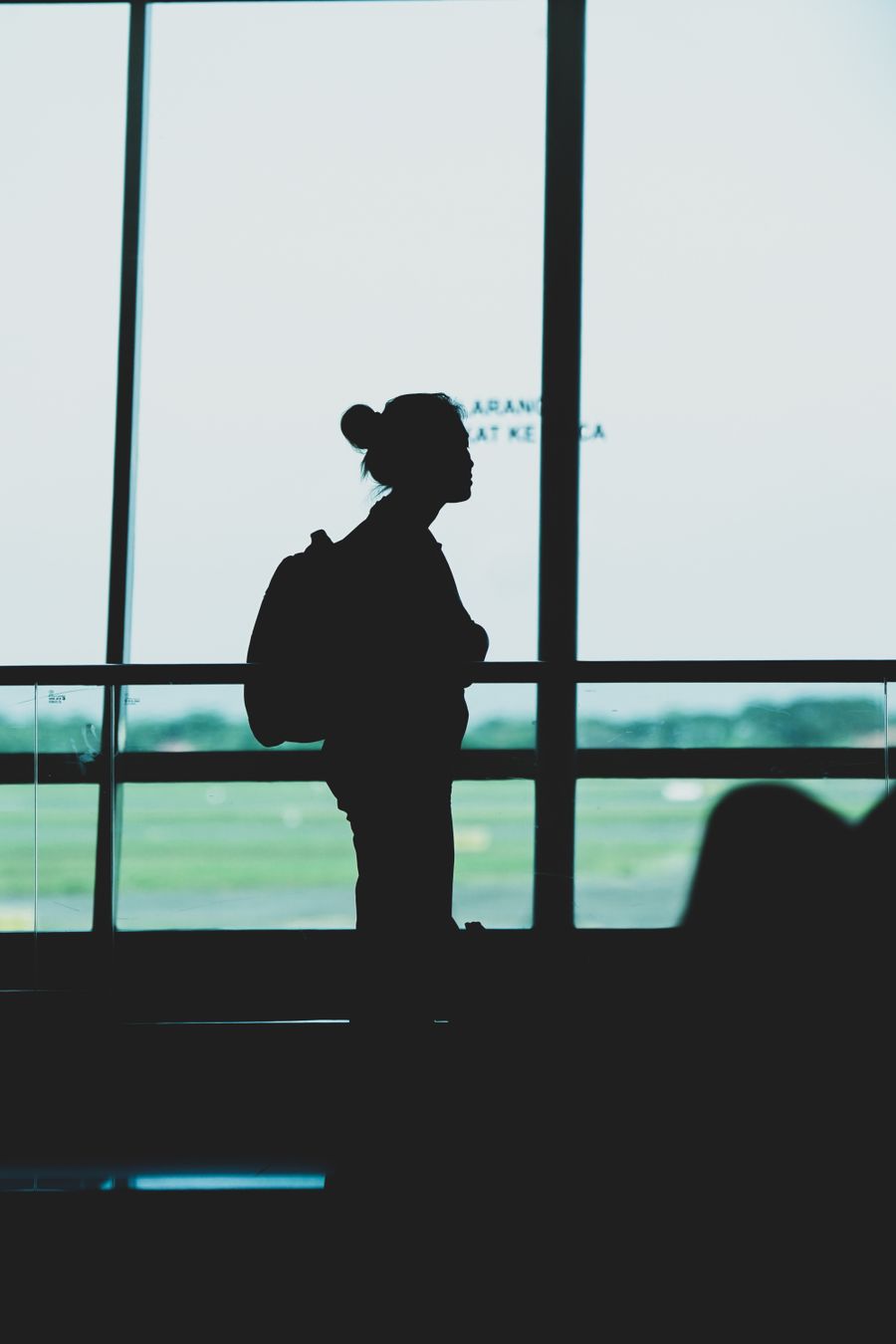 silhouette of a woman with a backpack standing at an airport terminal — Works through flaky airport Wi-Fi once loaded — for inputs already entered.