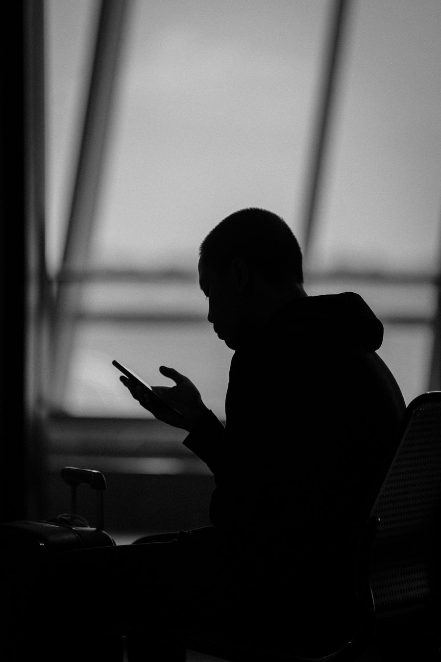 Silhouette of a man using a smartphone in an airport terminal in Surabaya, Indonesia. — Docs: Grupo da família: localização compartilhada, planos de jantar resolvidos em minutos.