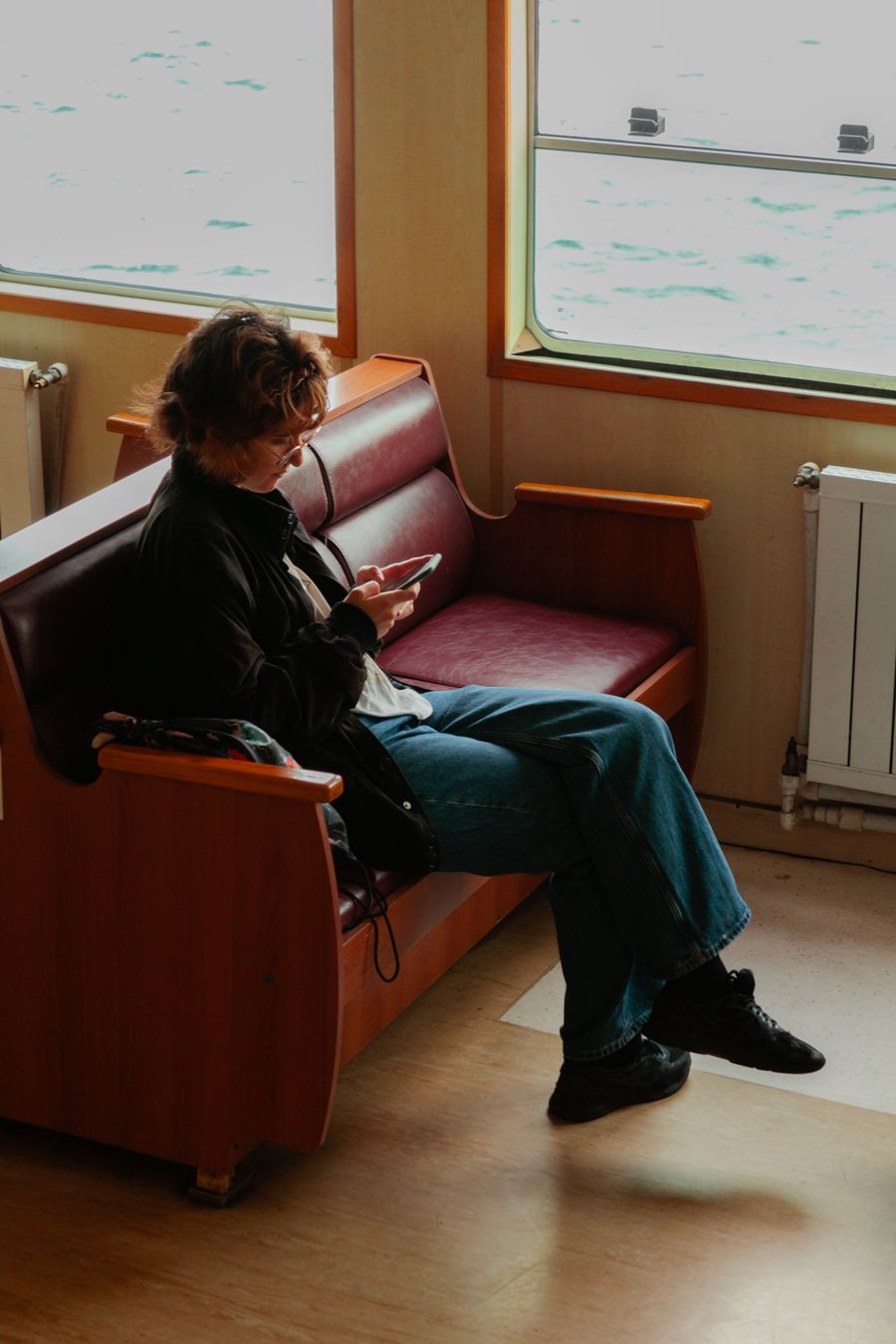 A woman sitting comfortably on a ferry, enjoying a peaceful journey. — Café office: hotspot running, video call stable, no hotel Wi-Fi roulette.