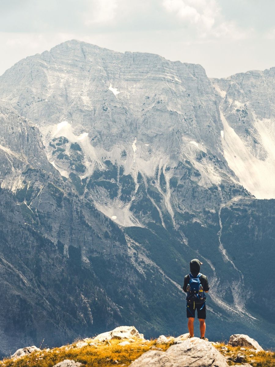 hiker admiring majestic albanian mountains — A road trip por Mozambique: paradas de combustível planejadas, playlist baixada, mapa offline.