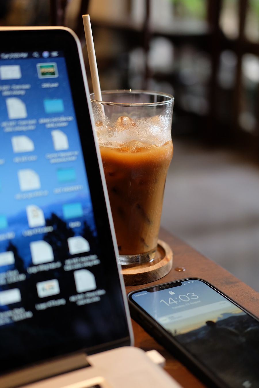 coffee shop workspace with laptop and iced coffee — Downtown, connected: the eSIM finds the fastest local network on its own.