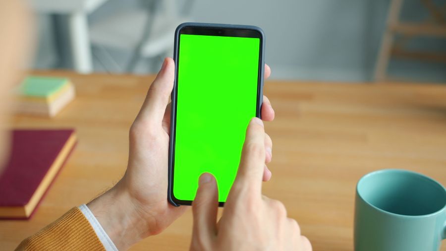 person using smartphone with green screen at desk — Night markets and late trains — connected the whole way through.