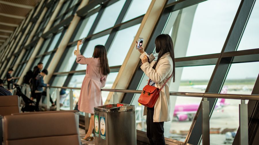 young travelers taking photos at shanghai airport — Dia de feira em Brazil: pesquise, traduza, pague pelo celular.