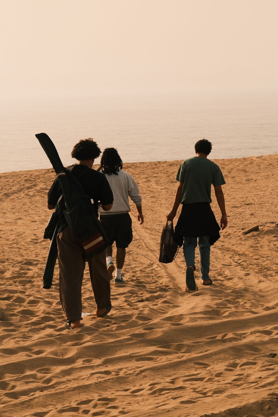 three friends walking on a sandy beach at sunset — Support: Suporte 24/7 — humanos mais o Tele Agent, o tempo todo.