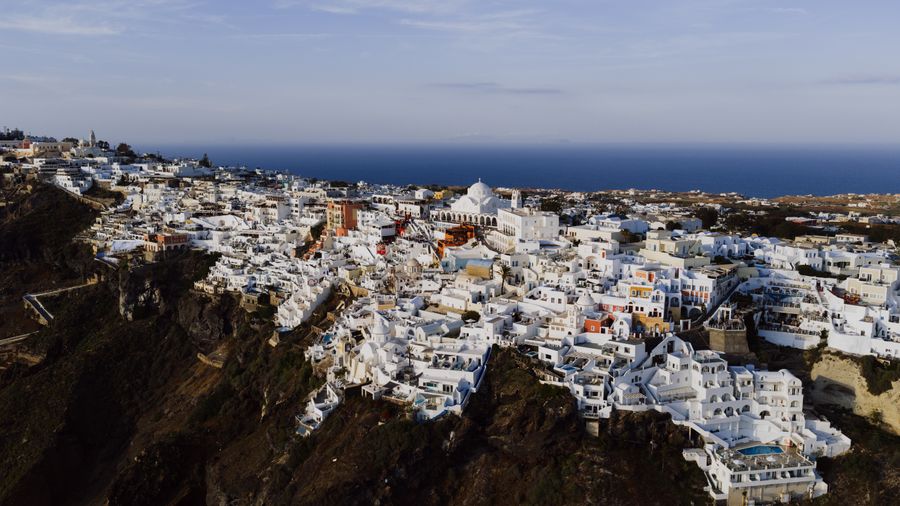 aerial view of fira santorini s white structures — Luzes da cidade depois de escurecer — o eSIM não liga para a hora.