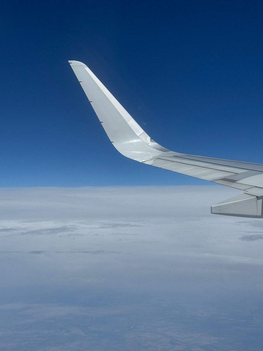airplane wing above the clouds on a clear day — Festivais em Mozambique: ponto de encontro fixado, amigos achados na multidão.