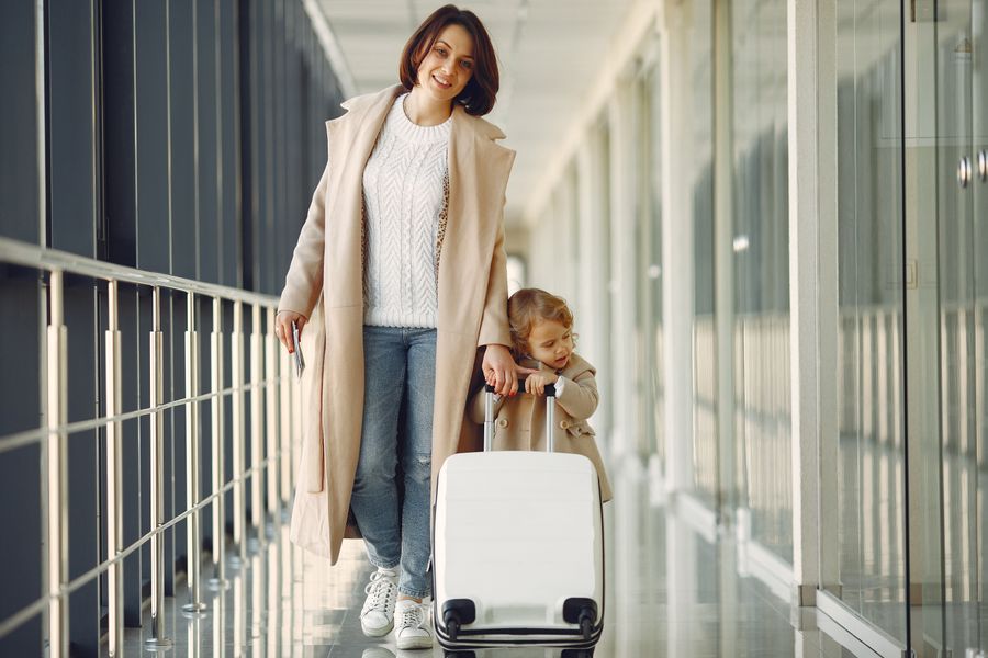 positive mother and daughter with suitcase in airport corridor — The group chat stays live across every border you cross.