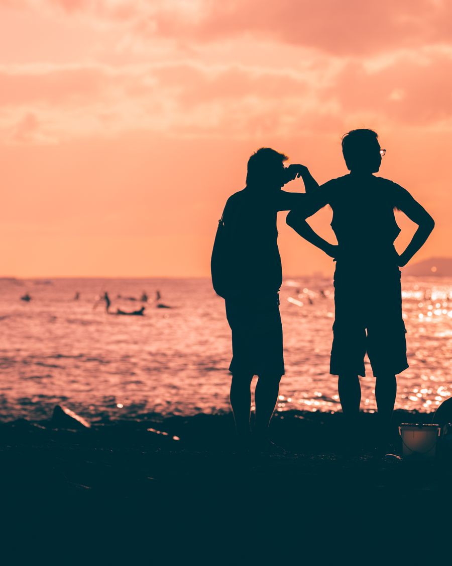 silhouette of 2 men and woman standing on beach during sunset — Developers: Praças e calçadões: videochamadas para casa com a vista atrás.