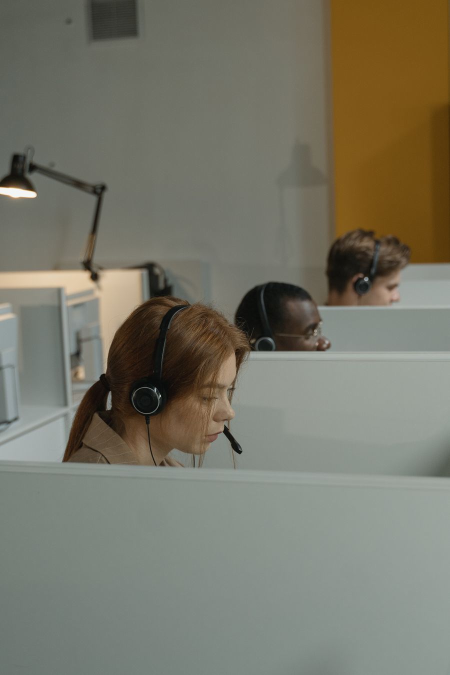 a woman with headset inside a gray cubicle — Mercados de Timor-Leste: pechinche com o conversor aberto, pague com um toque.
