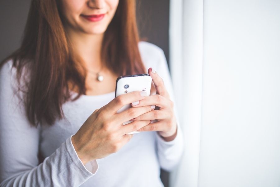 close up portrait of a young woman typing a text message on mobile phone — Luz do porto em Guinea-Bissau: backups de fotos subindo antes de você sentar.