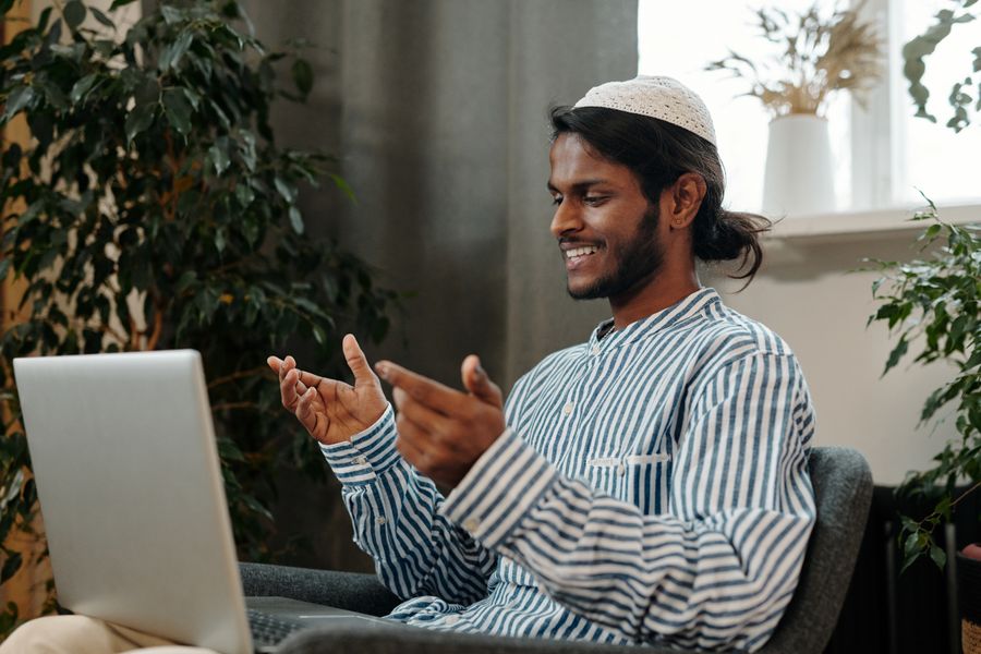man video calling using a laptop while sitting on a chair — The capability matrix lists everything eSIM Installation Guide does — no asterisks.