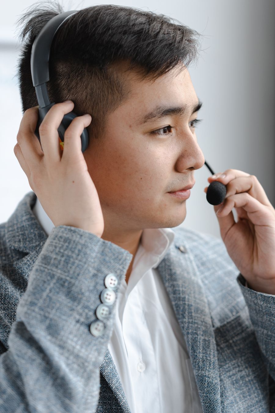 man in gray plaid jacket holding headset — O escritório da janela: e-mails enviados em algum lugar sobre o oceano.